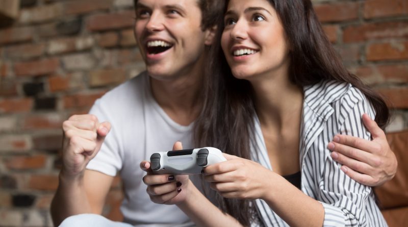 PlayStation czy XBOX – co jest lepszym wyborem dla gamera? Wesoła para grająca na kosnoli